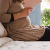 Mujer embarazada leyendo un libro sentada sobre la funda nórdica farm de si som dos.