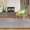 Salón con butaca de terciopelo color verde sobre alfombra de lana kansei kp alfombras a medida en color gris