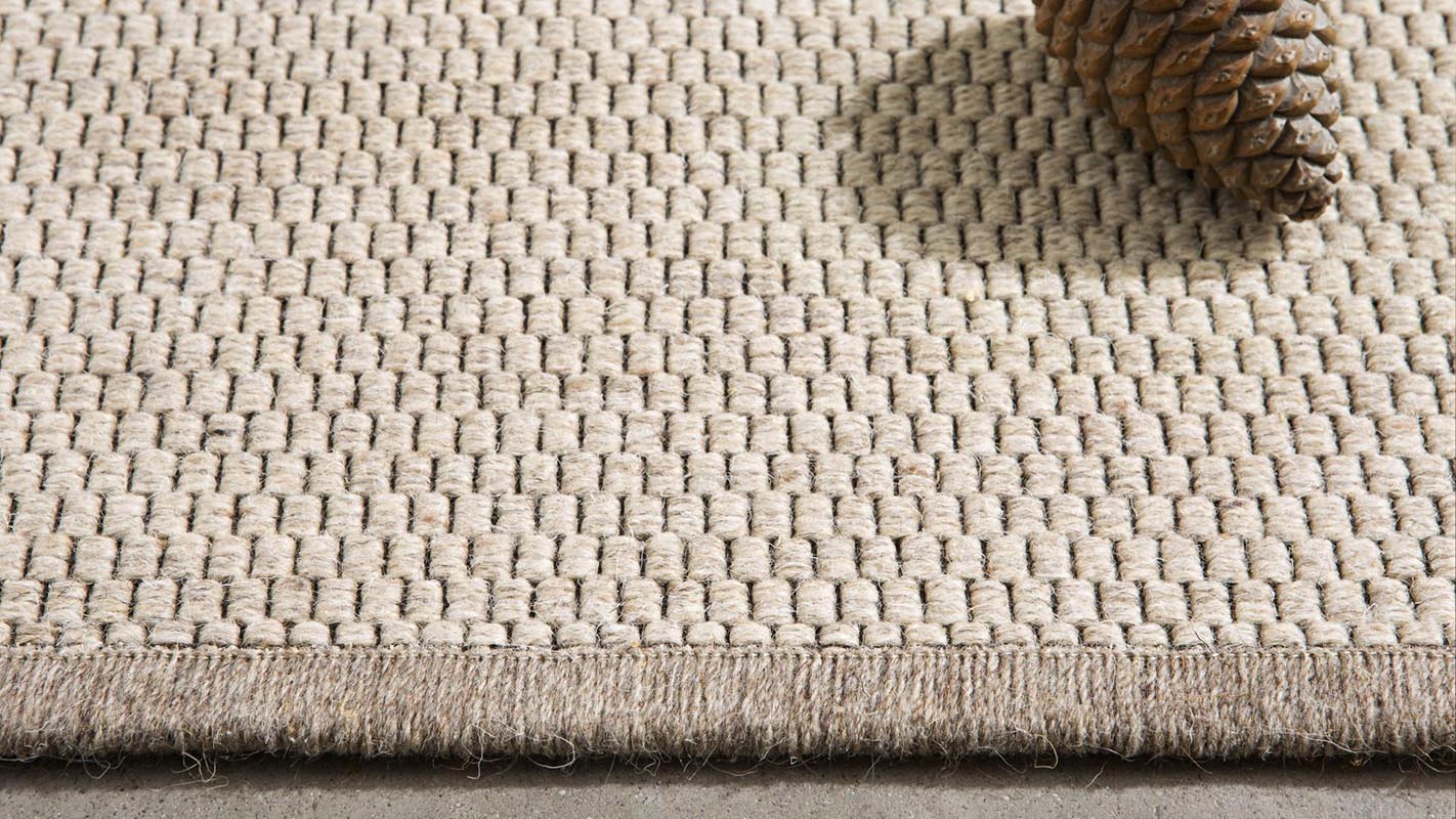 alfombra fina de lana eskila kp alfombras a medida en color beige con una piña encima