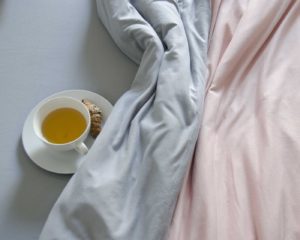 Ropa de cama sisomdos en gris y rosa con taza de te al lado