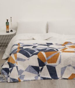 Colcha divertida habitaciones adolescentes Sisomdos Seventies, tejido jacquard 100% algodón diseño geométrico azul naranjas.