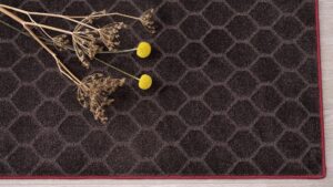 Flores amarillas y secas sobre alfombra a medida KP diseño hexágonos con remate rojo sencillo.