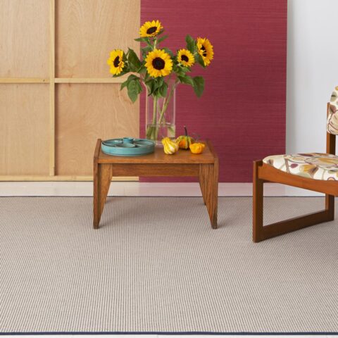 Habitación con alfombra a medida lana Knit de KP lanzadera beige claro, mobiliario madera, remate oscuro. Decoración floral