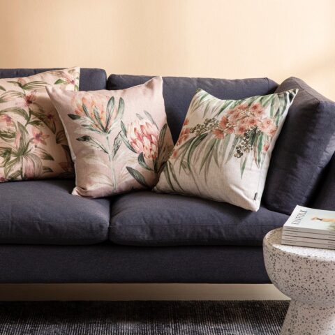 Cojines Kas Australia combinados. Modelos Tarah y Myrta en tonos rosas sobre sofá azul.