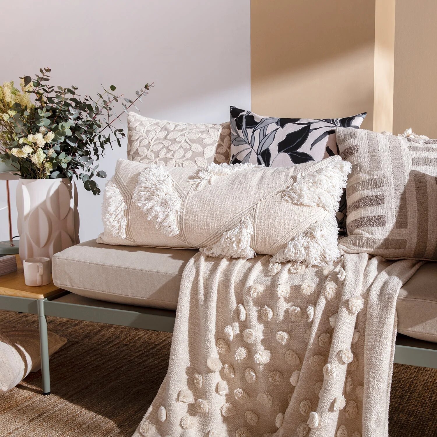 Plaid Lia Kas Australia sobre sofá beige, diseño pompones color crudo. Algodón 100%. Comprar online Fernández Textil