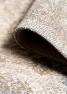 Detalle espesor y textura en alfombra vintage hecha en India, tonos topo con notas de azul y beige. Fácil de pisar.